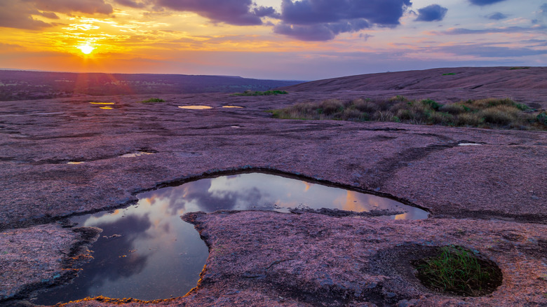 Enchanted Rock landscape with a small pool of water at sunset in the Texas Hill Country