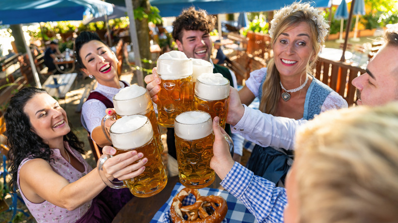A group of friends toasting with beer mugs while wearing traditional German attire