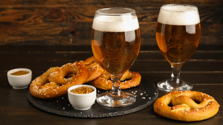 A plate with pretzels and two tulip-shaped beer glasses