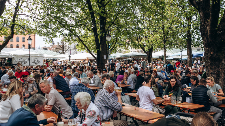 Crowds of people sitting at long wooden tables with beer