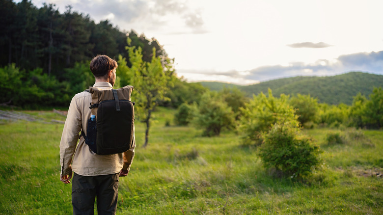 A man with backpack in grassy area