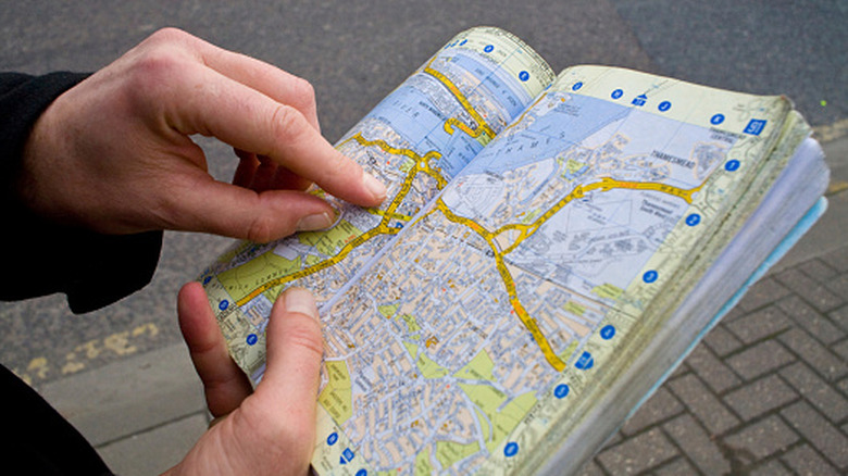 Hand with opened guidebook showing map