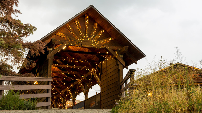 Covered wooden bridge lined with lights crossing a river in Nederland, Colorado