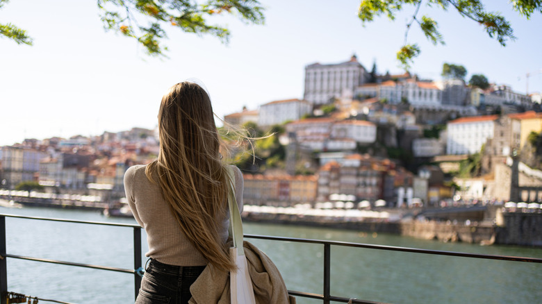 Long-haired woman looking over the Douro River and the city of Porto, Portugal, on a sunny day