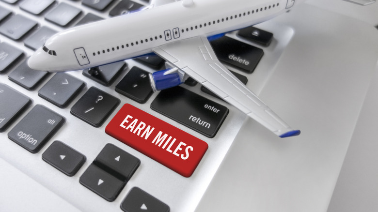 A keyboard with an "earn miles" key next to a toy airplane