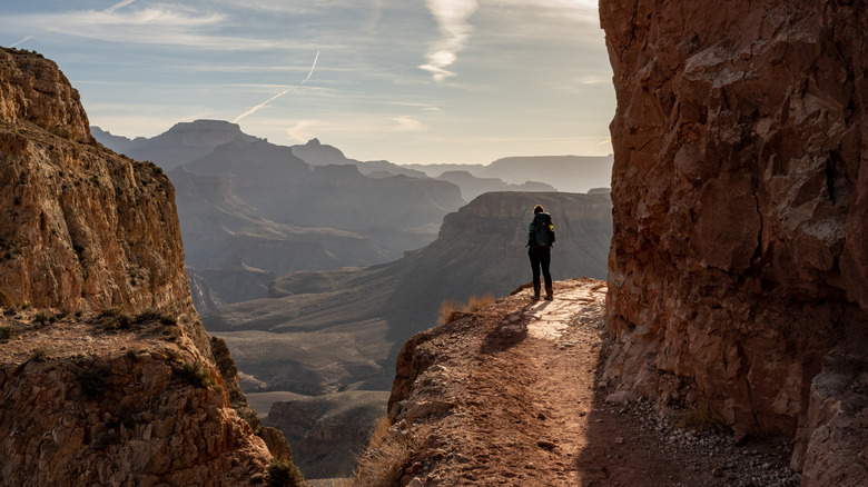 Woman hiker with backpack hiking along the cliff edge of Grand Canyon's South Kaibab Trail