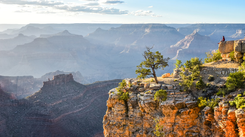 Hiker on the edge of a rock formation overlooking the vast Grand Canyon