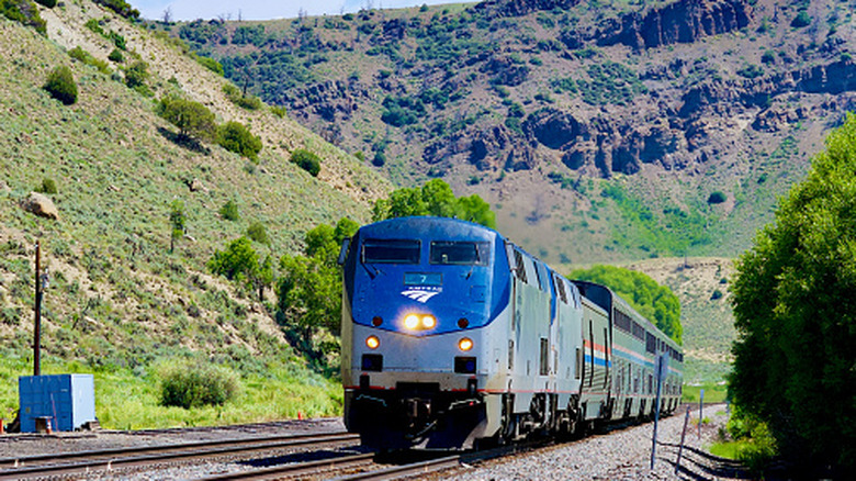 A train with mountains and greenery in the background