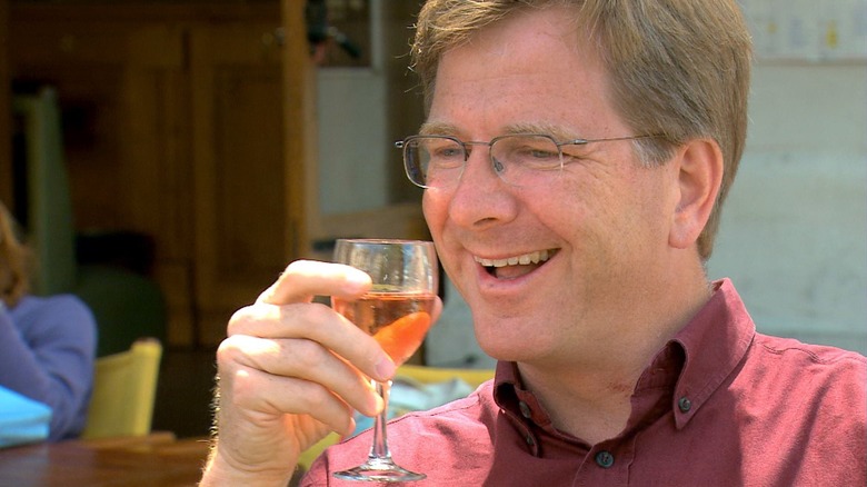 Rick Steves smiling and sipping on a glass of wine