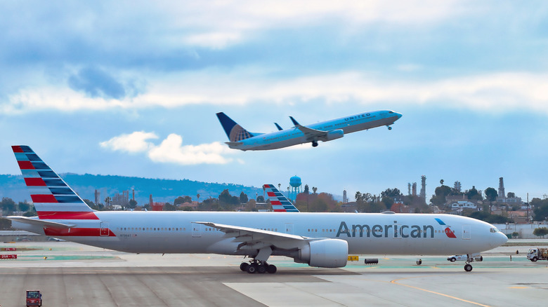 American Airlines plane on the runway with United Airlines plane taking off behind it.