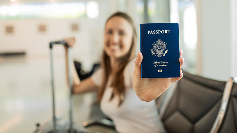 A smiling woman holds up her U.S. passport.