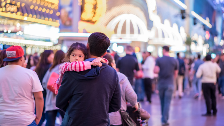 A man carrying his daughter while walking through the Fremont Street Experience