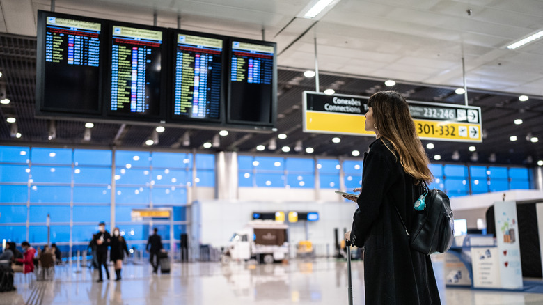 A person looking at a departures board in an airport