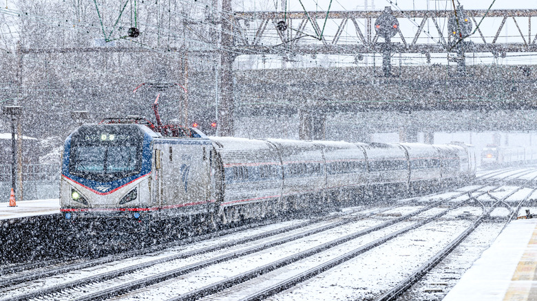 An Amtrak train departs a station in heavy snow