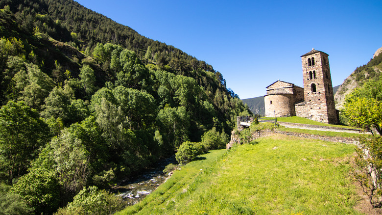 Church of Sant Joan de Caselles in the countryside of Canillo, Andorra, under a blue sky on a green hill