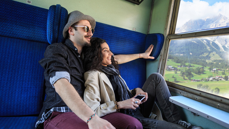 cheerful couple traveling aboard a train and enjoying the view