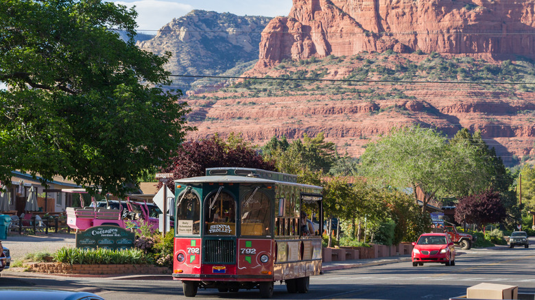 A tour trolley in the street with a massive red-stone mountain in the background