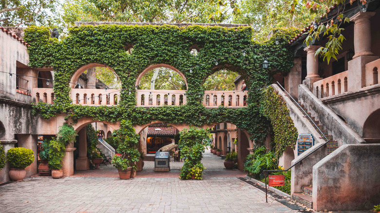 A cobblestone courtyard with vine-covered arches