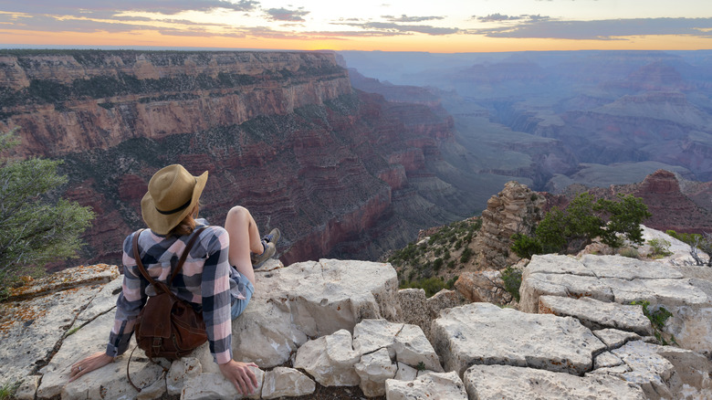 A female hiker sits on a viewpoint overlooking the Grand Canyon