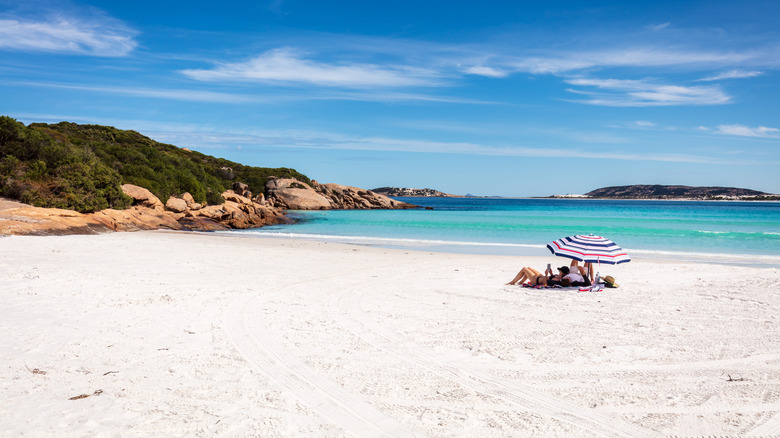 Sunbathers lay under an umbrella on the white sands of Wharton Beach in Esperance, Australia
