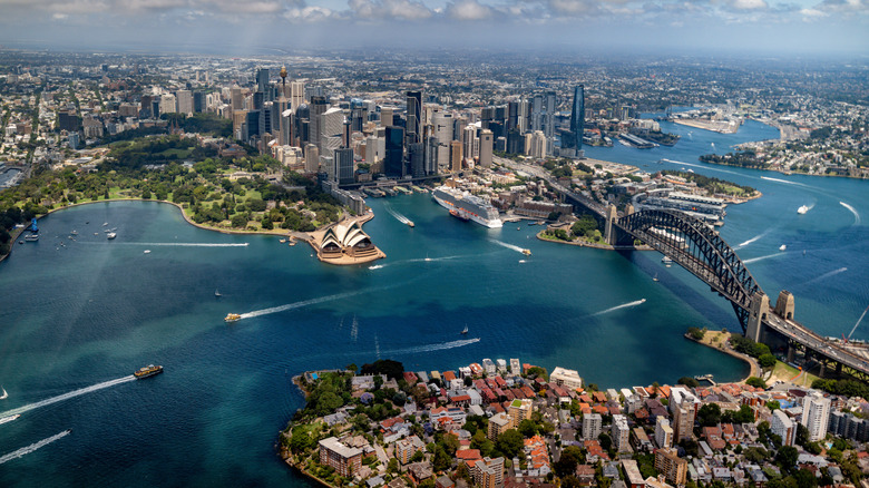 Aerial drone shot view of downtown Sydney, harbor, and bridge on summer day.