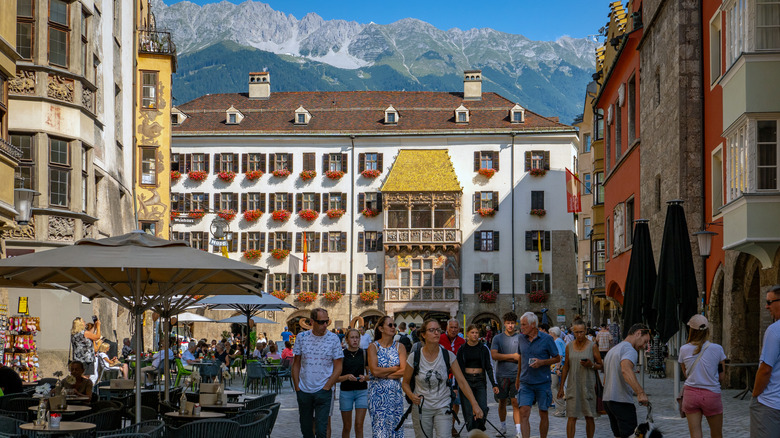 Tourists stroll through the courtyard in front of the Golden Roof in the Old Town of Innsbruck, Austria on a sunny day