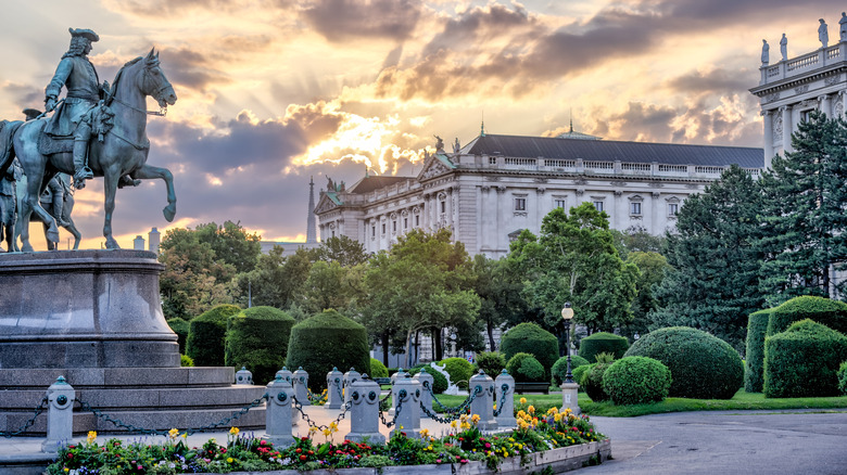 The Maria Theresa Memorial in Vienna, Austria at sunrise with flowers and a baroque building in the background