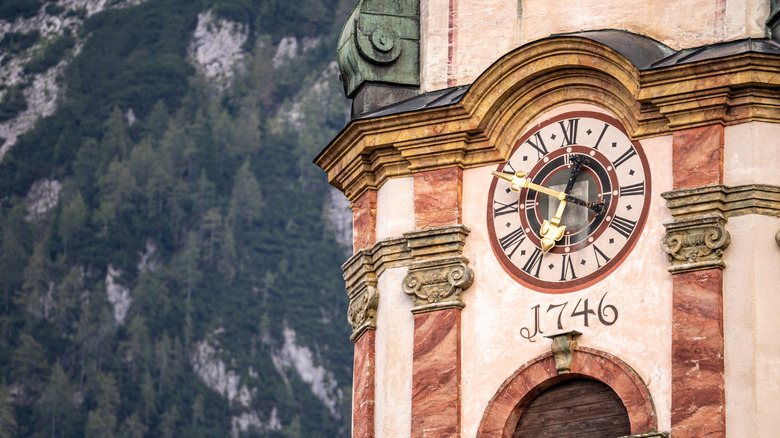 Close up of ornate clock tower in Mittenwald against a dramatic mountain peak
