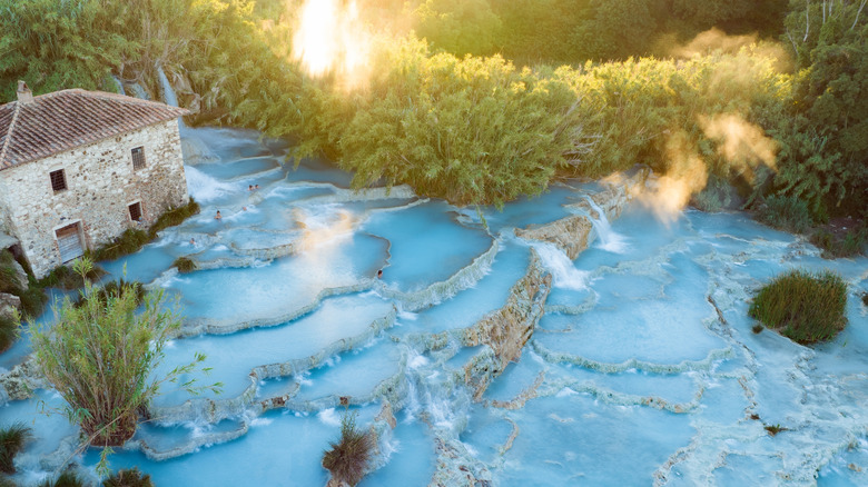 Blue terraces of Cascate del Mulino near an old building in the Italian countryside at dawn