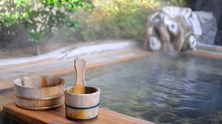 Wooden paddle and bucket on the edge of a wooden pool at a private outdoor onsen in Japan
