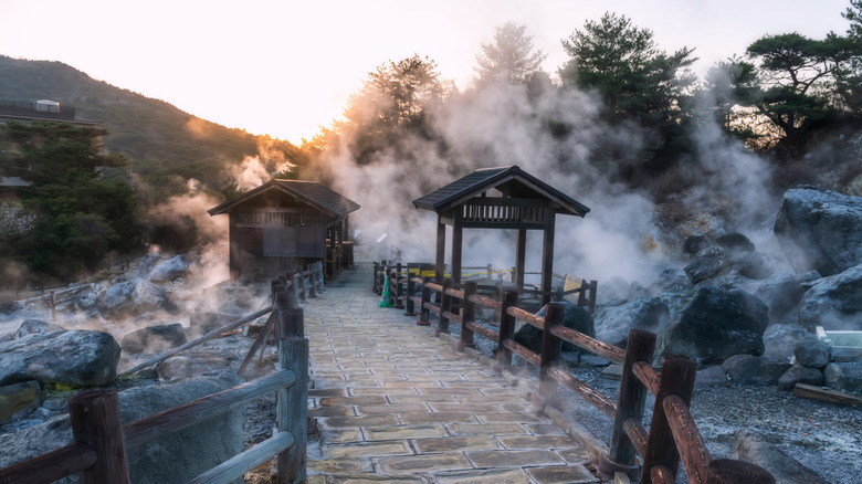 Stone bridge crossing an onsen while steam rises from the thermal waters