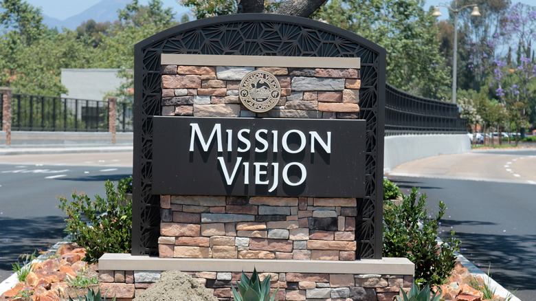 A sign for the city of Mission Viejo next to a street