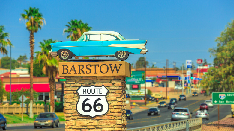 A sign for Barstow and Route 66, topped with a classic car motif