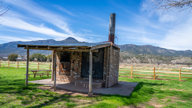 An old stone building in a green feild with mountains in the distance in Rockin' River Racnh State Park, Arizona