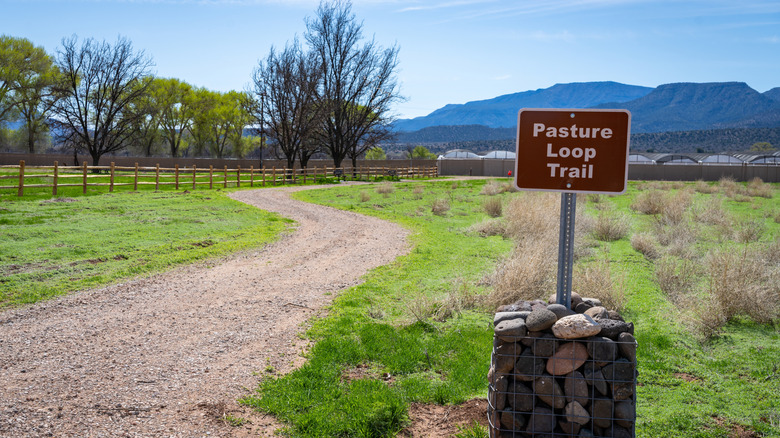 An sign indicates the Pasture Loop Trail next to a gravel path at Rockin' River Ranch State Park in Arizona
