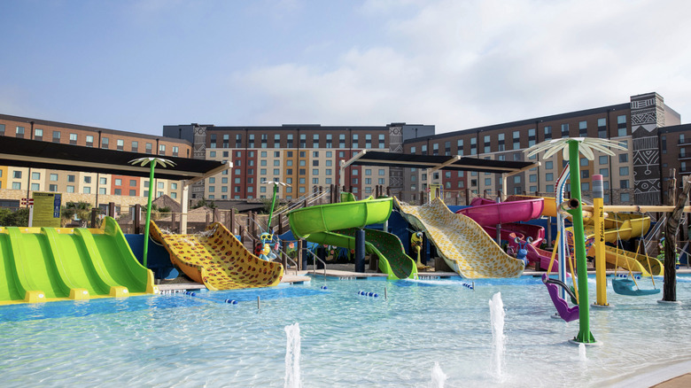 Outdoor waterslides and pool with resort hotel building in the background.