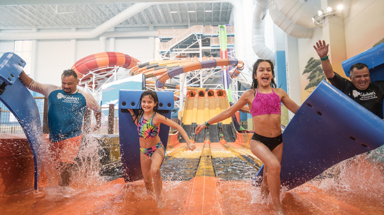 A family exits a thrilling waterslide with their foam mats at an indoor waterpark.