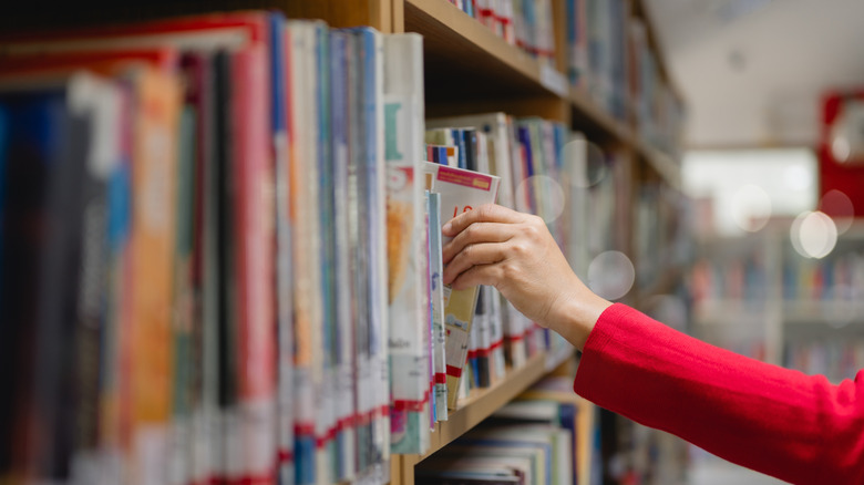 someone withdrawing a book from a library shelf