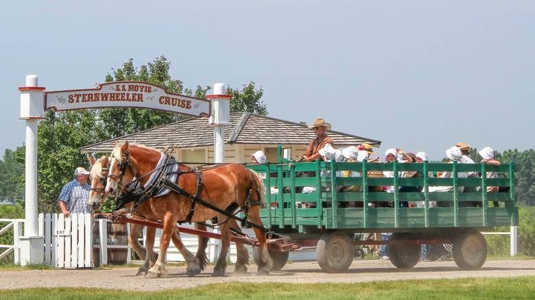 A horse pulls a wagon full of people dressed in western clothes at Heritage Park