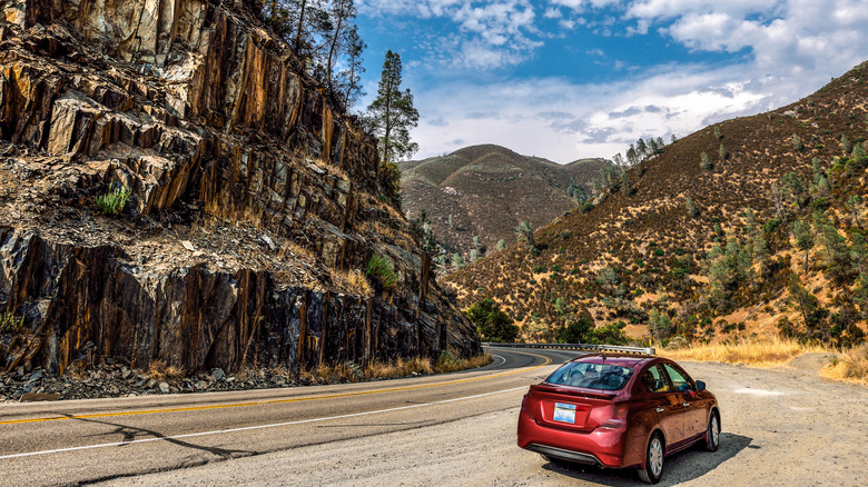 A car heading toward Yosemite National Park from Mariposa on Highway 140, surrounded by mountain cliffs