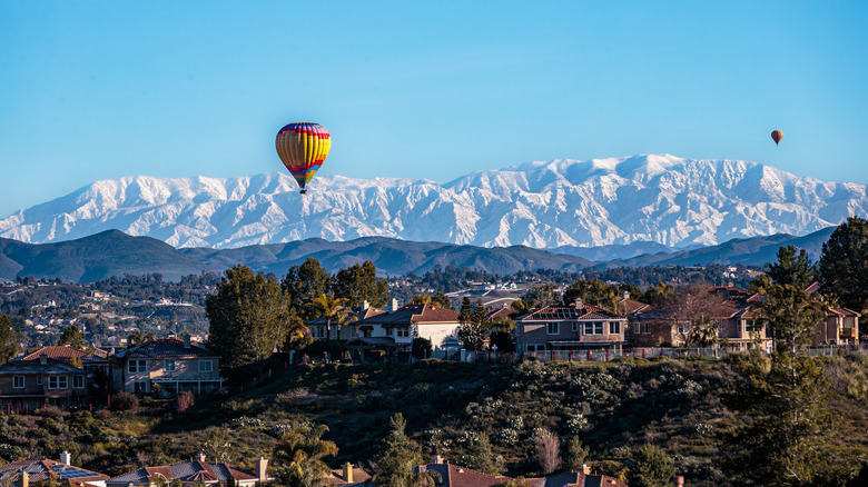 Snow-capped mountains and homes in Temecula Valley with hot air balloon visible.