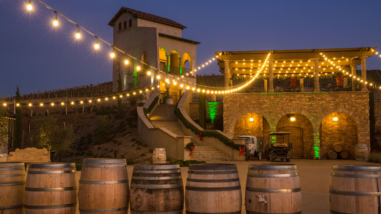 A line of wine barrels sits in front of Christmas lights and buildings in Temecula, California
