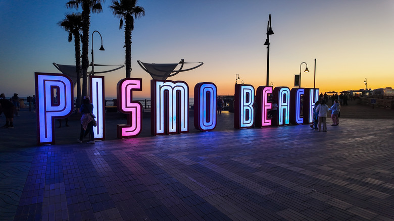 An illuminated sign for Pismo Beach at sunset