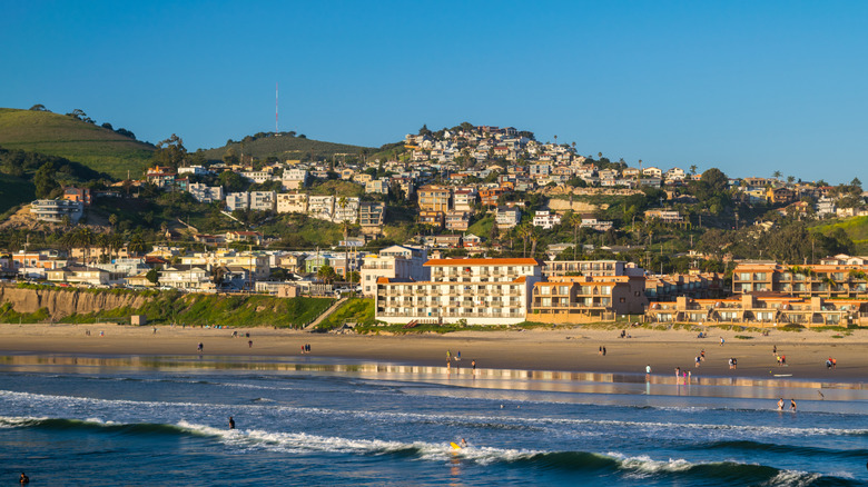 The sandy shores of Pismo Beach, California, with houses sitting on a hill