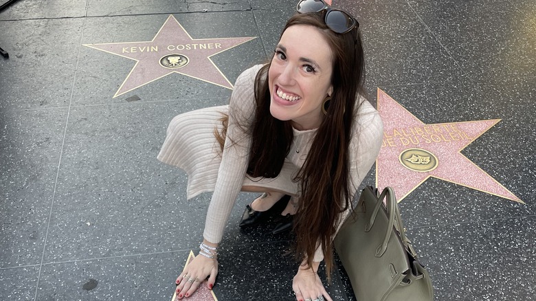 Brunette woman posing by stars on the Hollywood Boulevard Walk of Fame