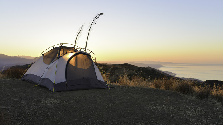 The sun rises behind a tent positioned on the coastline, above Santa Barbara, California.