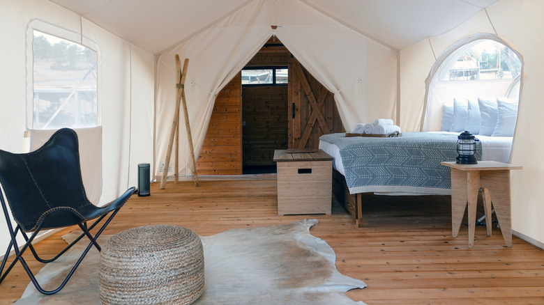 Inside a glamping tent with a bed and chair