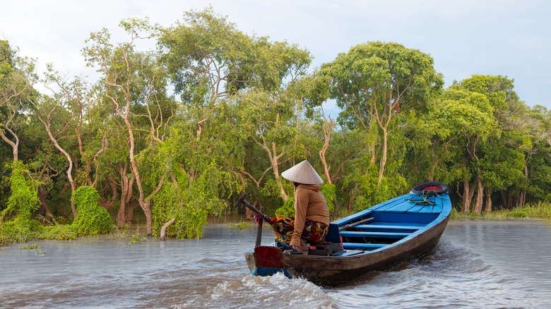 Fisherman in traditional pointed hat boating in Tonlé Sap Lake