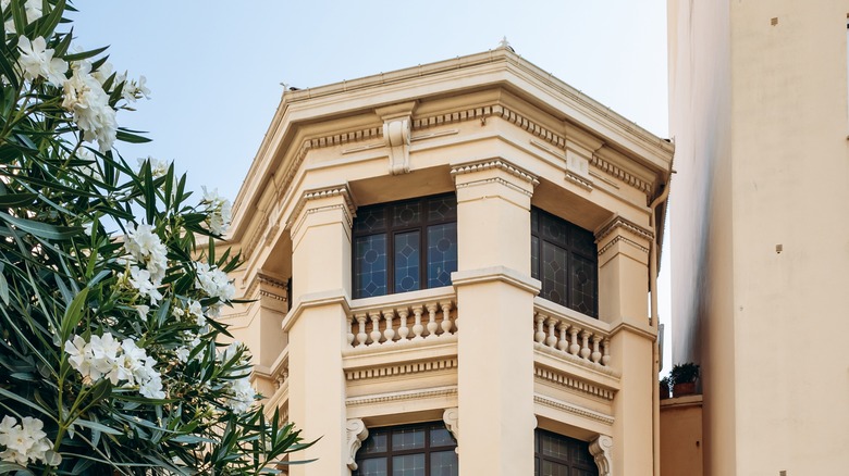 View of a mansion facade in Cannes with leaded glass windows and white flowers in the foreground on the left side