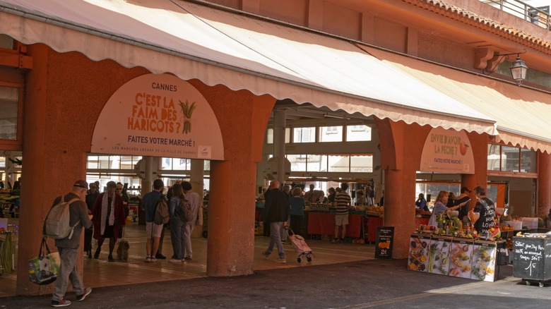 View of the entrance of the covered Forville Market in Cannes, France with shoppers and vendors visible